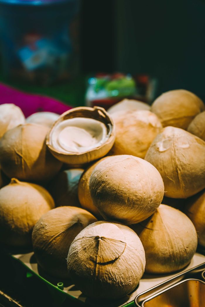 Close-up of fresh coconuts stacked at an outdoor market, ready for sale.