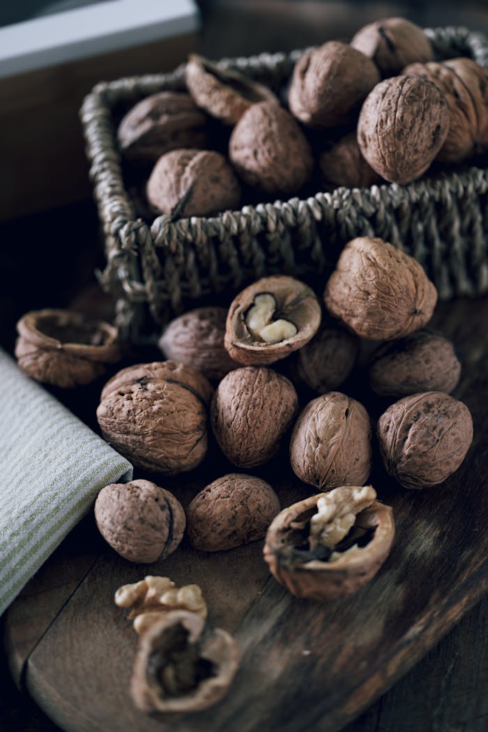 A collection of whole and cracked walnuts on a rustic wooden surface, perfect for culinary themes.