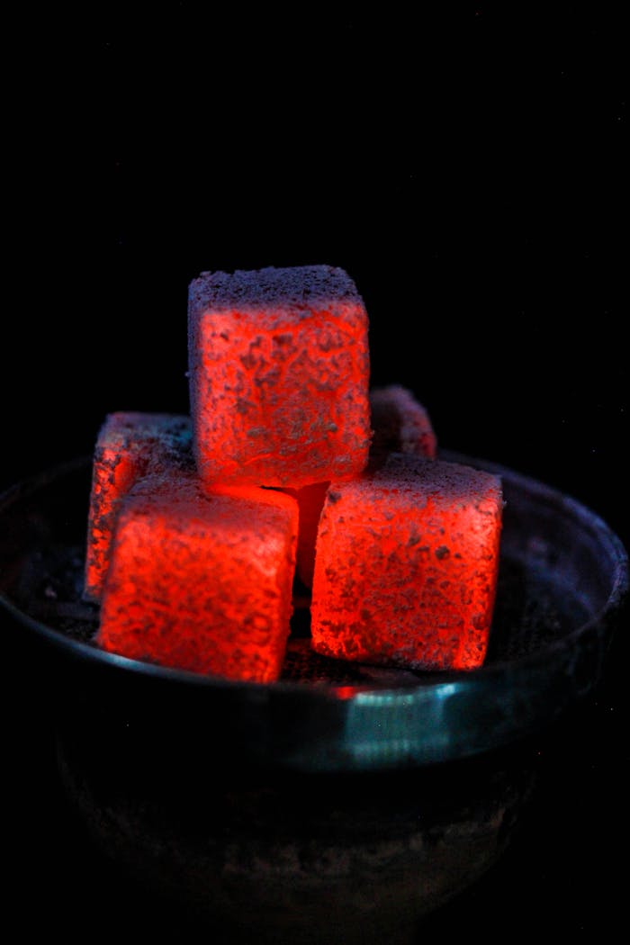 Close-up of glowing red charcoal cubes on a hookah bowl, showcasing intense heat.